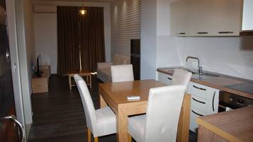 A modern kitchen with white cabinets, a wooden dining table, and white chairs.
