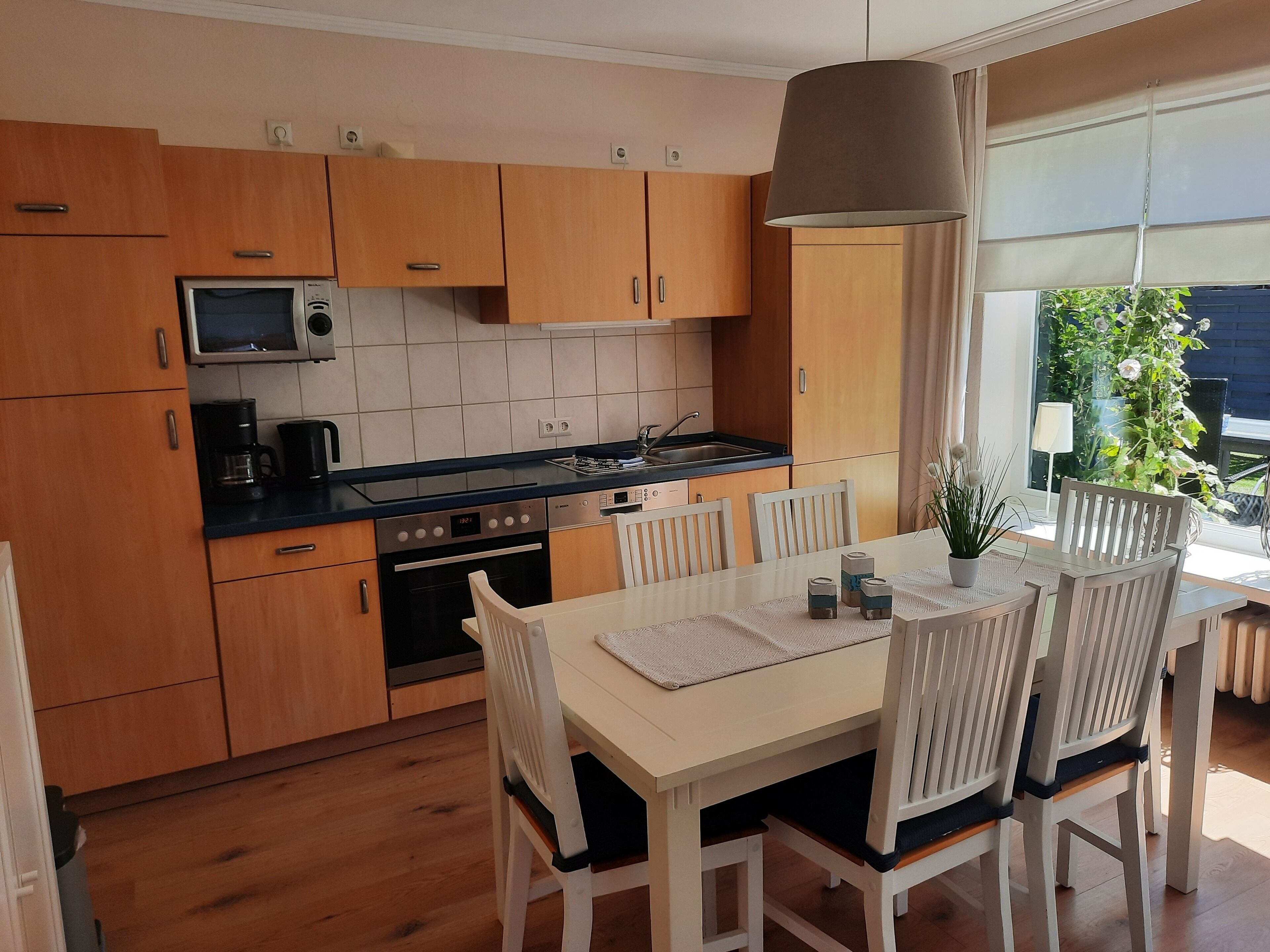 A modern kitchen with wooden cabinets, a microwave, stove, and a dining table with chairs.