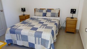 A bedroom with a bed, two bedside tables, and two lamps. - El Buen Samaritano Backpackers - Hostel (Paracas)