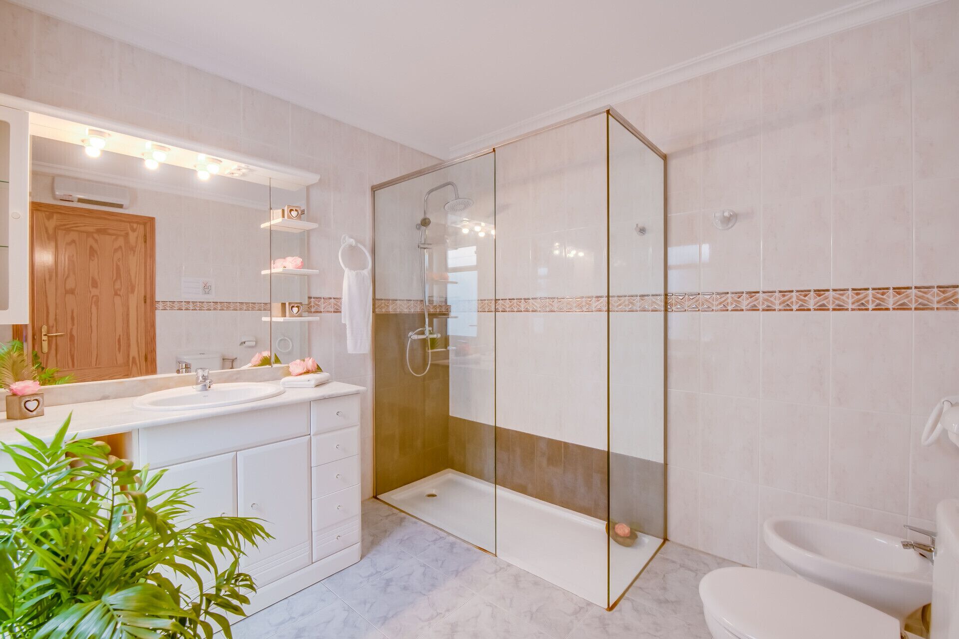 Un baño moderno con ducha envuelta en vidrio, tocador doble y un inodoro.