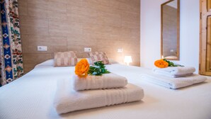 Une chambre d’hôtel avec un grand lit, deux oreillers, une table de chevet, un miroir et un rideau à motifs floraux.