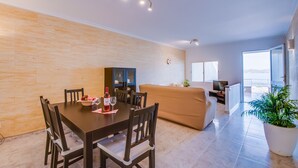 Un salon moderne comprenant un coin repas, un canapé, un téléviseur et une grande fenêtre offrant une belle vue.