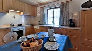 Una cocina acogedora con armarios de madera, una mesa de comedor con tazas de té, una tetera y una cesta de pan.