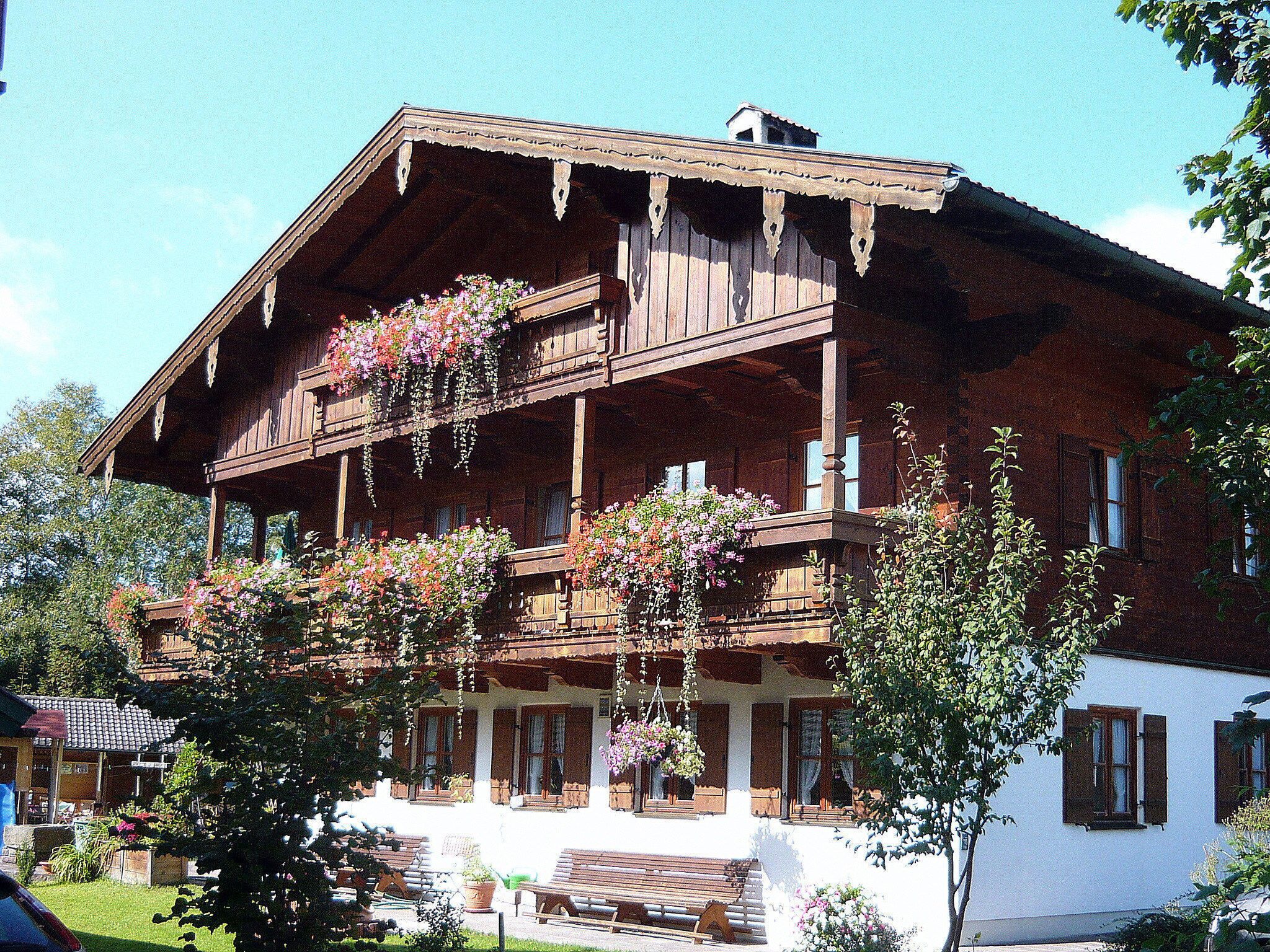 Un bâtiment traditionnel en bois, doté d’un balcon, de nombreuses fenêtres et de jardinières suspendues.