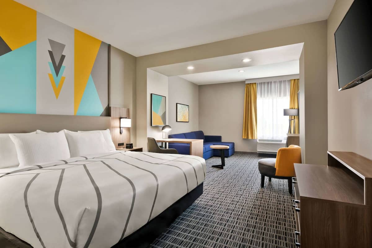 A hotel room with a large bed, a desk, a chair, and a TV.