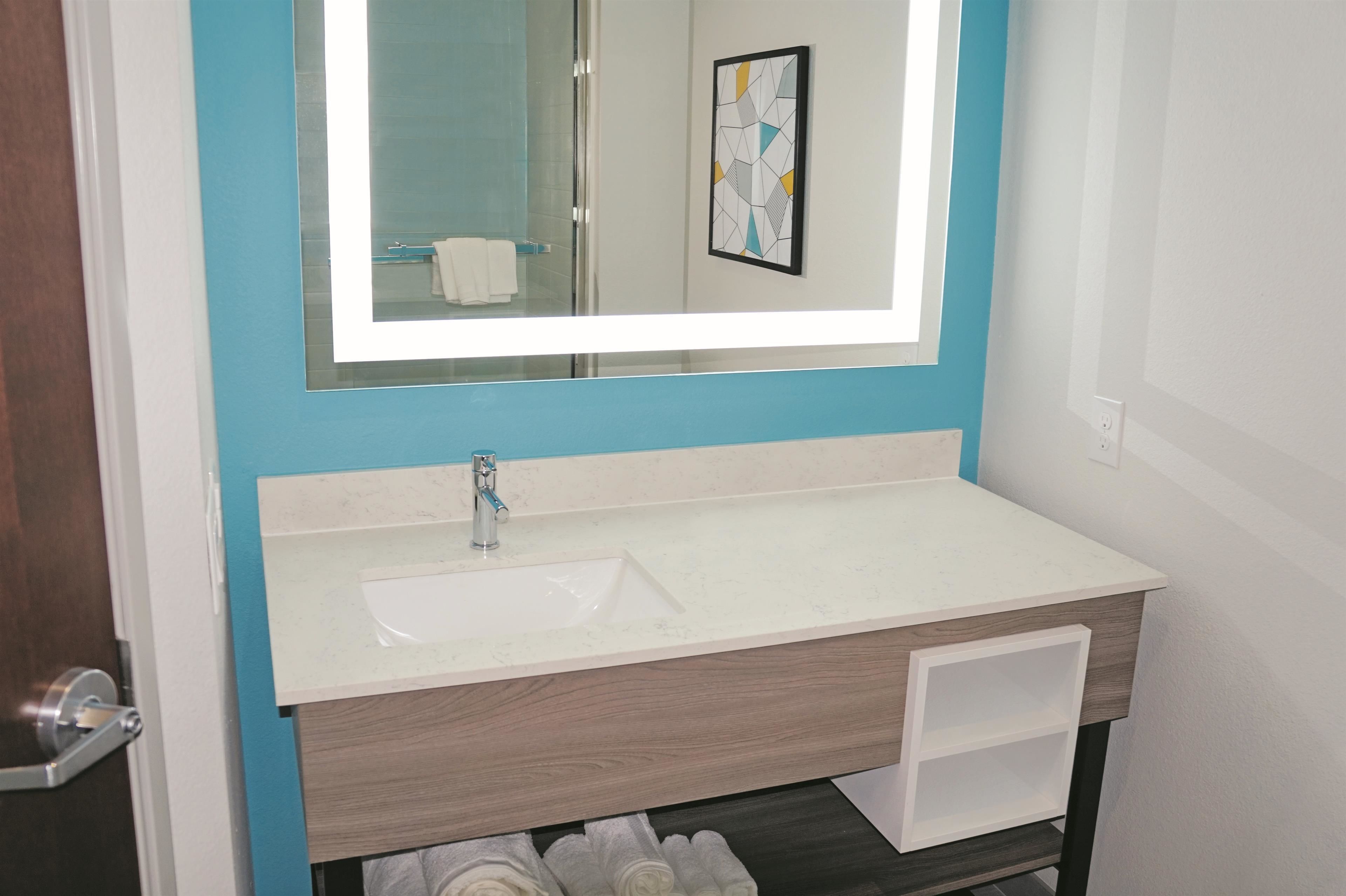 A bathroom with a white sink, a mirror, and a towel rack.