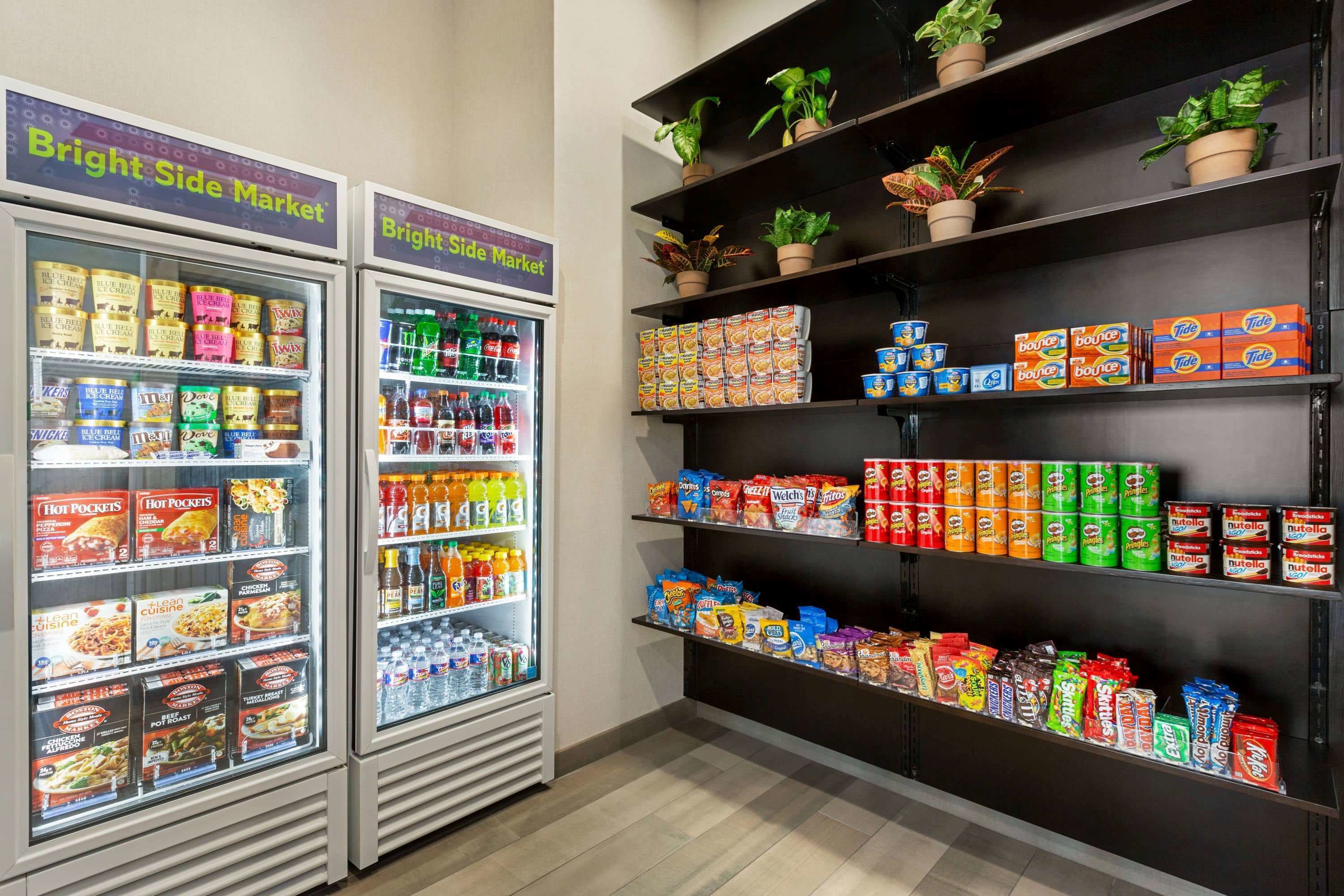 Twee koelvitrines met verschillende etensproducten en een plank vol snacks en drankjes.