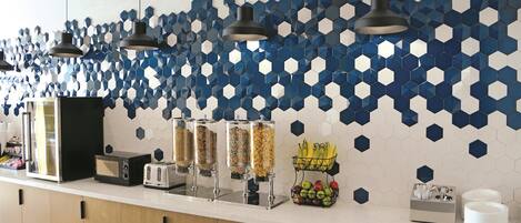 A breakfast bar with a hexagonal tile backsplash, a toaster, a refrigerator, and a fruit basket.