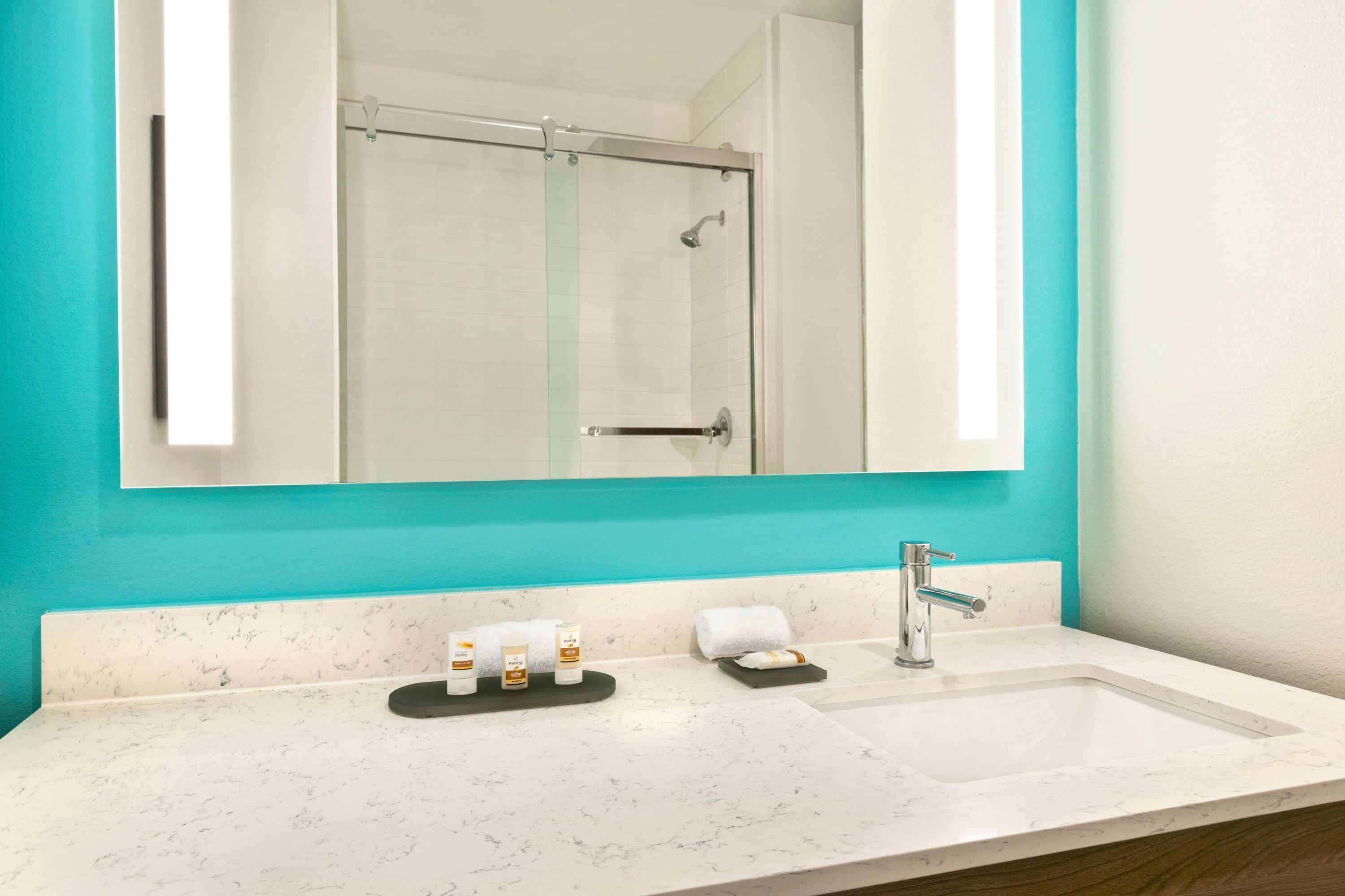 A bathroom with a white sink, a mirror, and a glass shower enclosure.