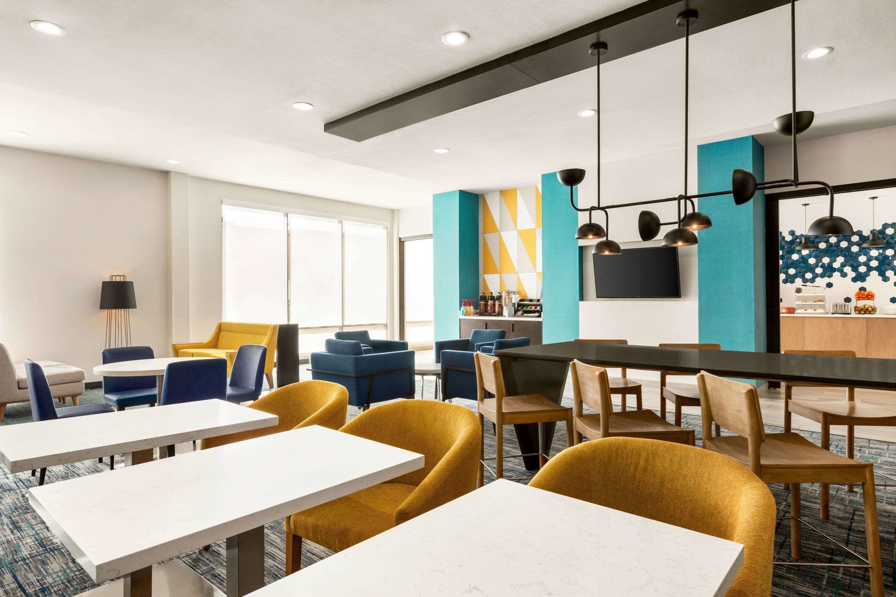 Una habitación de hotel moderna con comedor, cocina y un amplio ventanal.