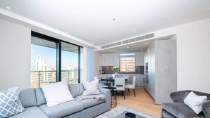 Un appartement moderne avec un canapé gris, un coin repas et une cuisine.