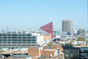 A cityscape with modern buildings, including a distinctive red triangular building and a tall skyscraper. - Luxurious Victoria Home by the Apollo Theatre (London)