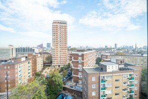 A high-rise building with multiple floors and balconies, surrounded by other residential buildings. - Luxurious Victoria Home by the Apollo Theatre (London)