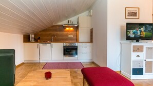 A compact kitchen with white cabinets, a built-in oven, and a wooden ceiling. - Vacation apartment 7 for up to 4 people, with 2 extra bedrooms and kitchen in the living/dining area (Reit im Winkl)