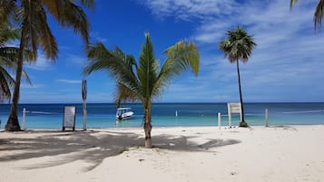 Pantai pribadi, pasir putih, kursi berjemur, dan handuk pantai