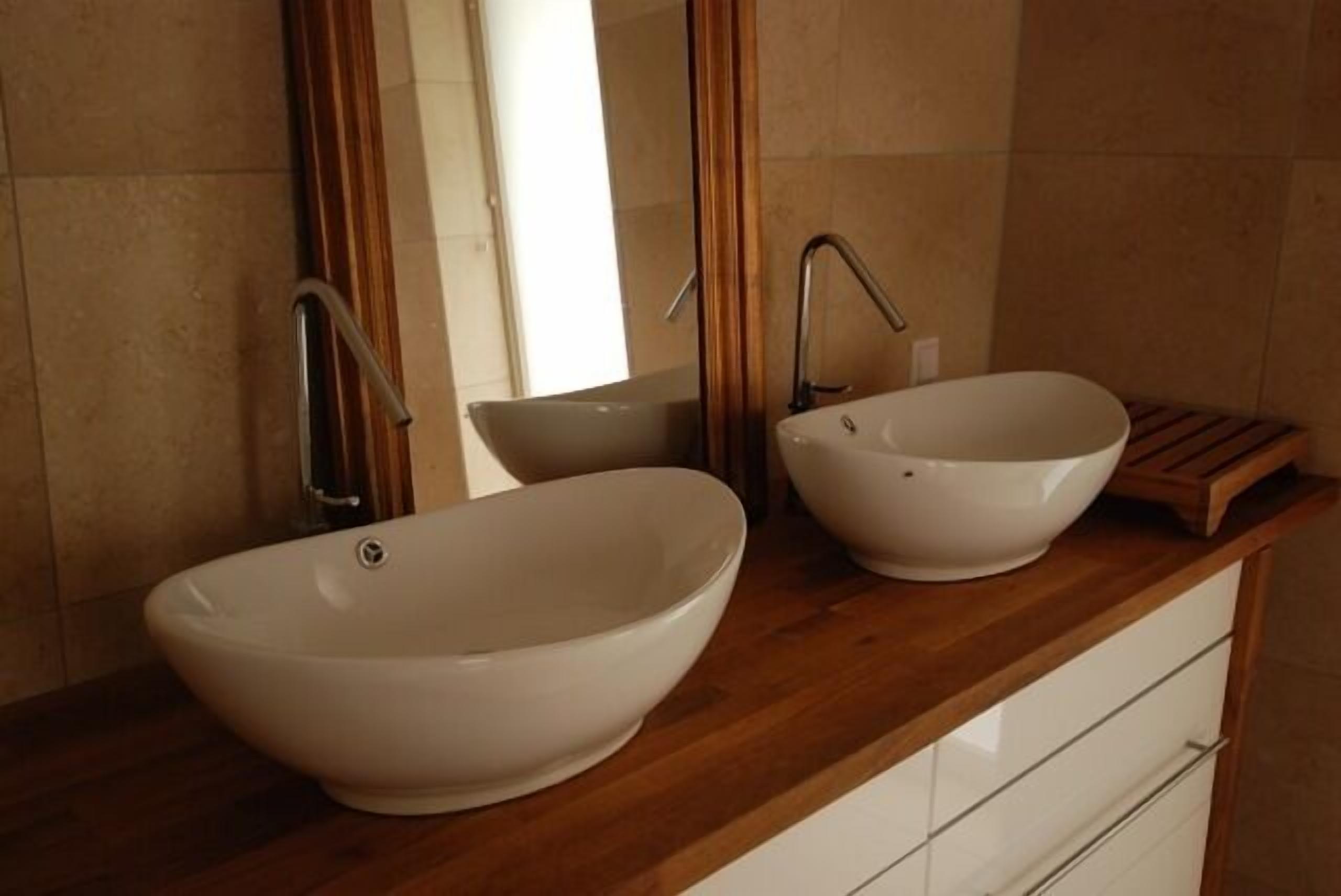 Une salle de bain avec deux vasques blanches et un meuble-lavabo en bois.