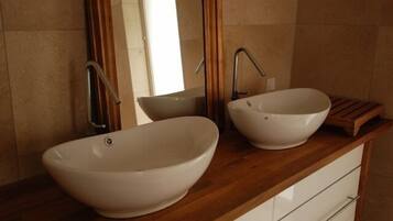 Une salle de bain avec deux vasques blanches et un meuble-lavabo en bois.