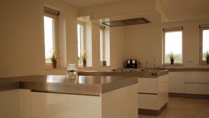 A modern kitchen with a central island, built-in appliances, and large windows providing natural light. - Directly at the Wadden Sea, part of UNESCO World Heritage. Calm/Fun at beach (Wierum)