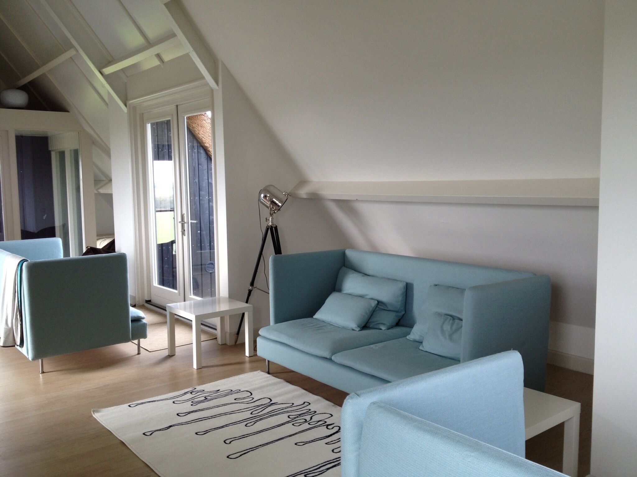 A modern living room with a light blue sofa, a small white table, and a floor lamp.
