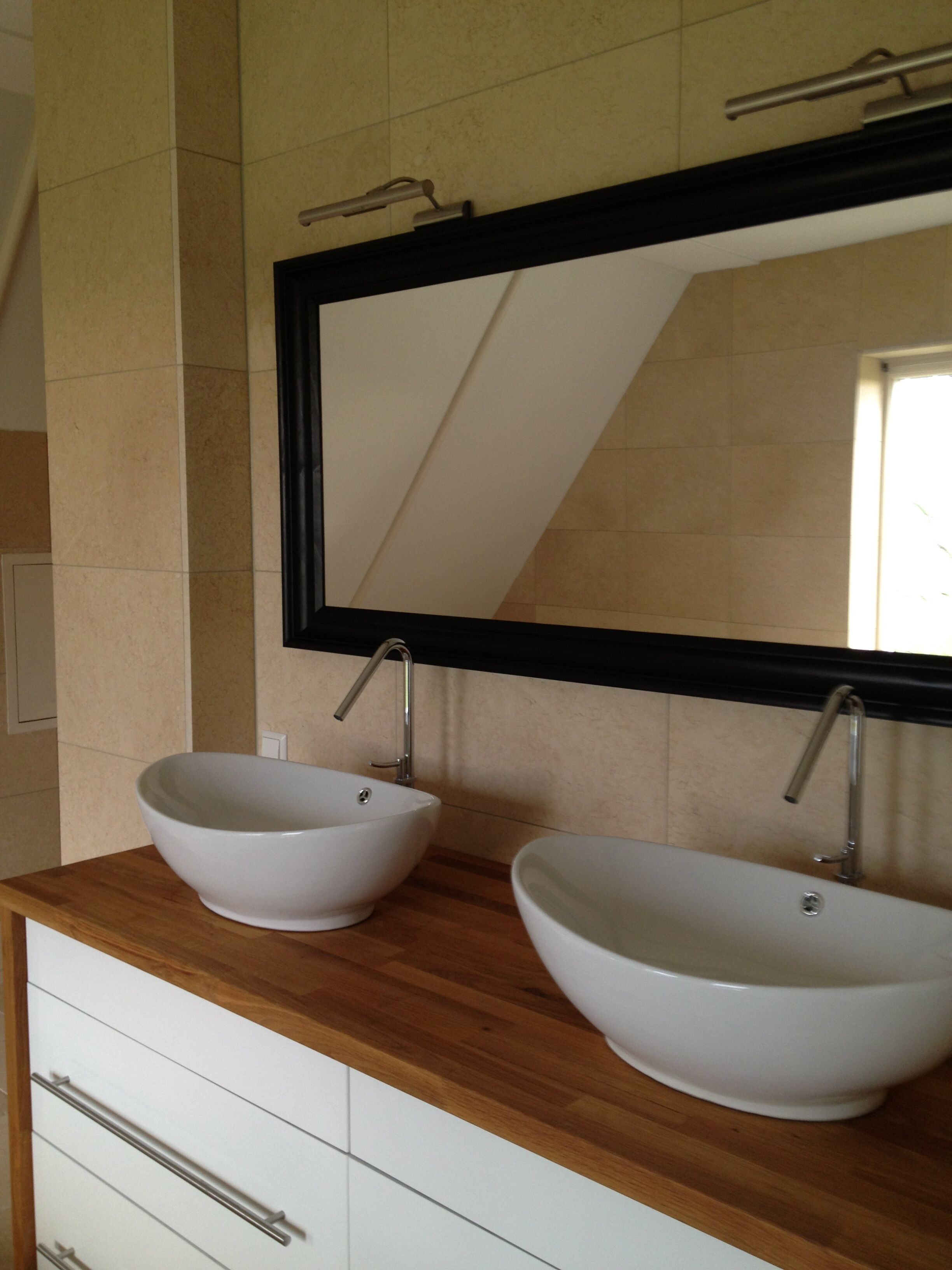 A bathroom with two vessel sinks, a wooden countertop, and a large mirror.