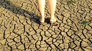 A person standing on cracked ground.