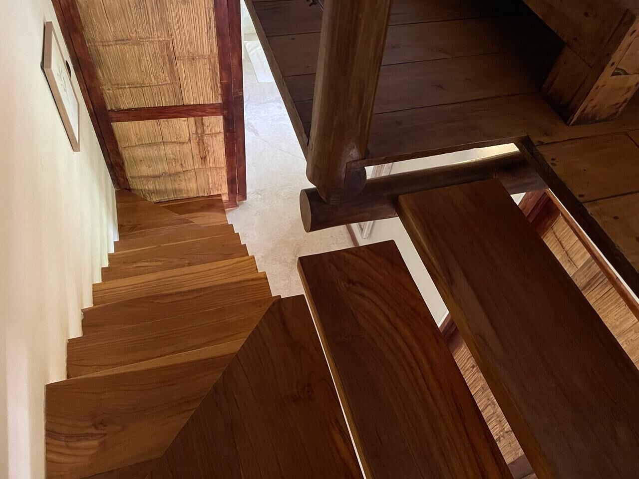 A wooden staircase with a wooden handrail and a white wall with a framed picture.