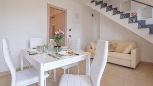 A dining area with a white table and chairs, a staircase, and a beige sofa. - 2 bedroom awesome home in Framura (SP) (Framura (SP))