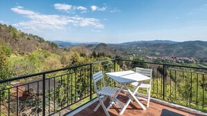 A balcony with a table and two chairs overlooking a mountainous landscape. - 2 bedroom amazing home in Carro (SP) (Carro (SP))