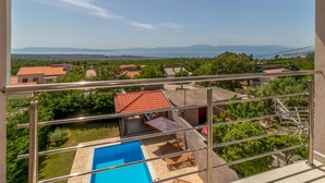 A balcony with a clear view of a swimming pool, outdoor furniture, and a red-roofed building. - Stunning home in Smrika with sauna (Smrika)