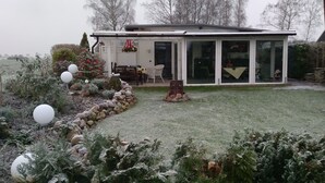 Ett hus med en täckt uteplats, en stenmur och ett julgran.