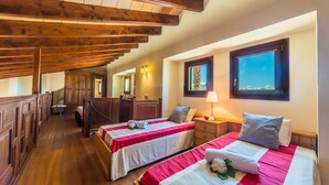 A hotel room with two beds, wooden beams on the ceiling, a window with a view, and a mirror. - Maison près de la mer Goya avec piscine à Alcudia (Alcúdia)