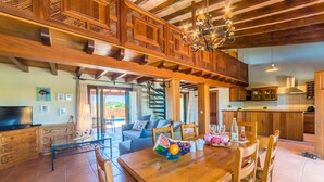 A spacious dining area with a wooden table set for two, a sofa, and a staircase leading to an upper level. - Maison près de la mer Goya avec piscine à Alcudia (Alcúdia)