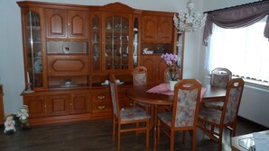 A dining room with a wooden cabinet, a chandelier, and floral chairs.