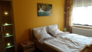 A bedroom with a bed, a nightstand, a lamp, and a painting on the wall.