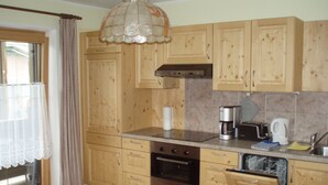 Una cocina con armarios de madera, estufa, cafetera y lavavajillas.