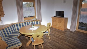 Un salón acogedor con una mesa redonda de madera, un sofá a rayas y sillas de madera.