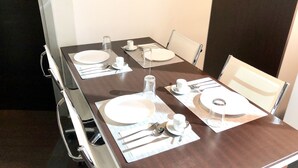 A dining table set with plates, cutlery, and glasses, with chairs around it. - Gemini Guest House (Rome)