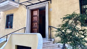 A building entrance with a wooden door, a balcony with metal railings, and a staircase leading to the entrance. - Gemini Guest House (Rome)