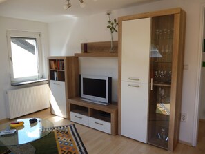 Ein modernes Wohnzimmer mit Fernseher, Holzschrank und Glastausenke.