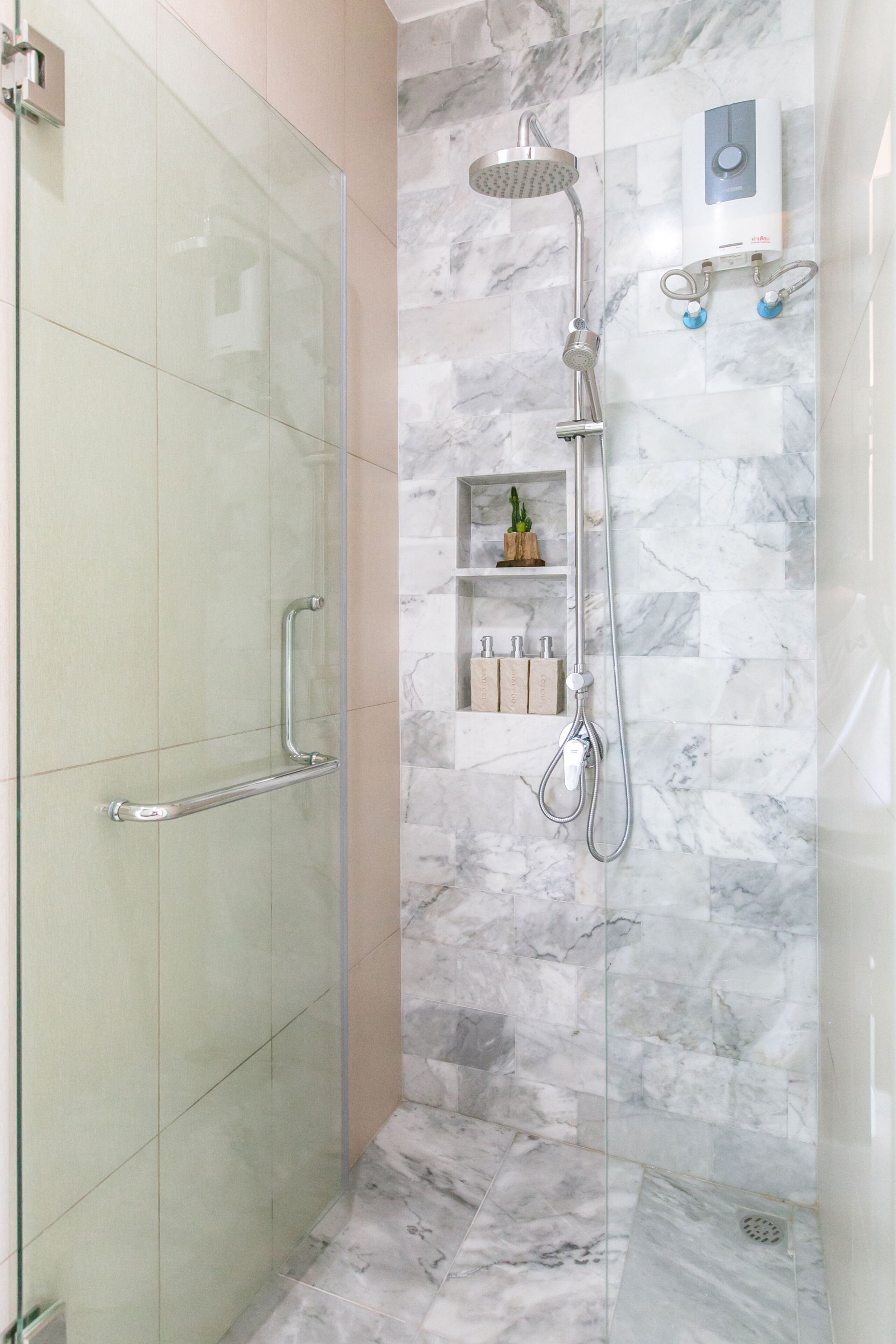 A modern bathroom with a glass shower enclosure, a handheld showerhead, and a wall-mounted control panel.