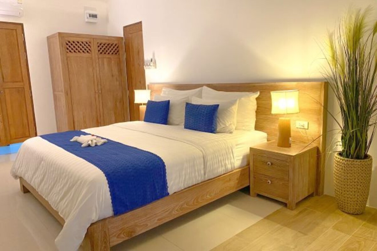 A neatly made bed with a blue and white bedspread, a wooden headboard, and bedside lamps.