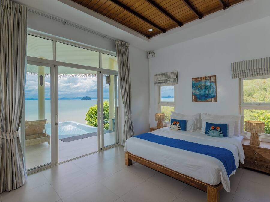 A bedroom with a large bed, a view of the sea, and a balcony.