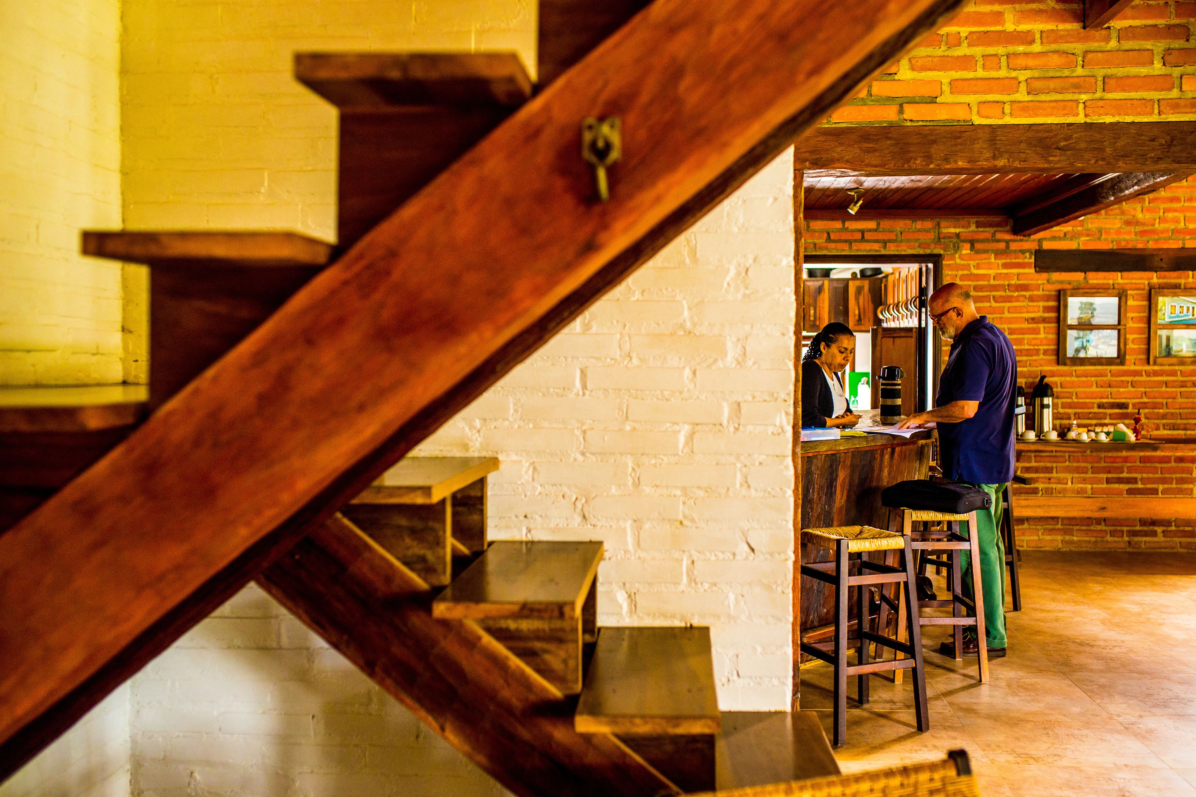 A wooden staircase leading to a bar area with brick walls and a white ceiling.