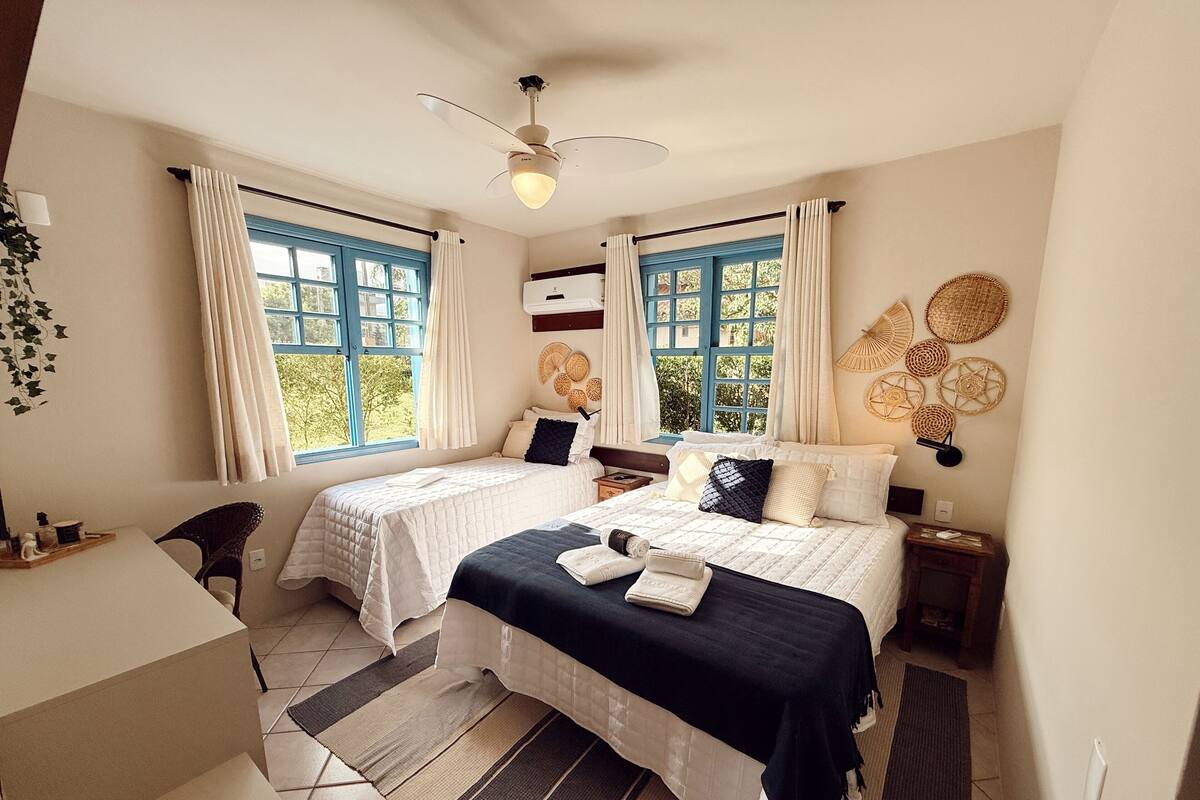 A double bed room with two windows, a ceiling fan, and a wall-mounted air conditioner.