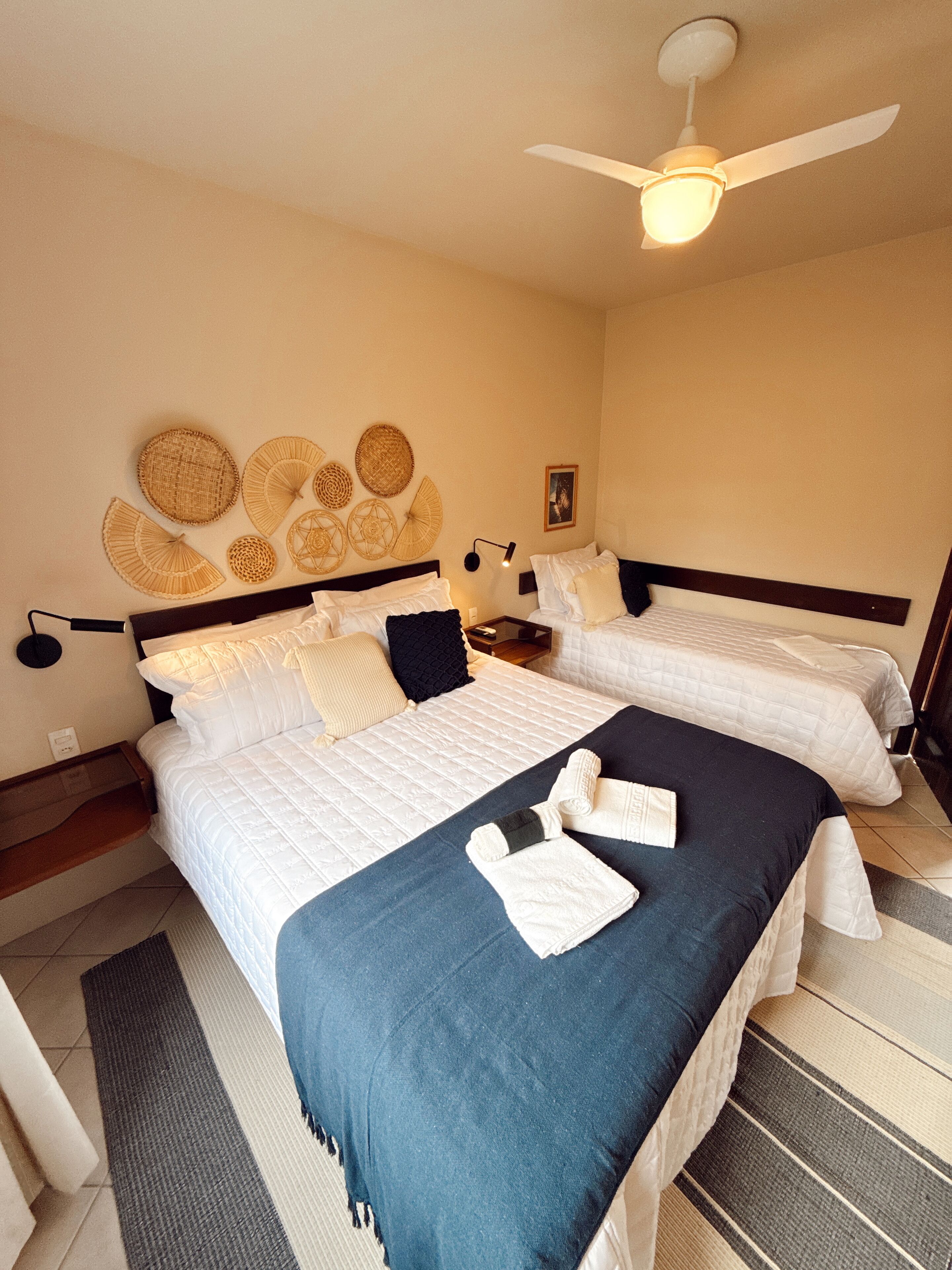 A hotel room with two beds, a ceiling fan, and decorative wall art.
