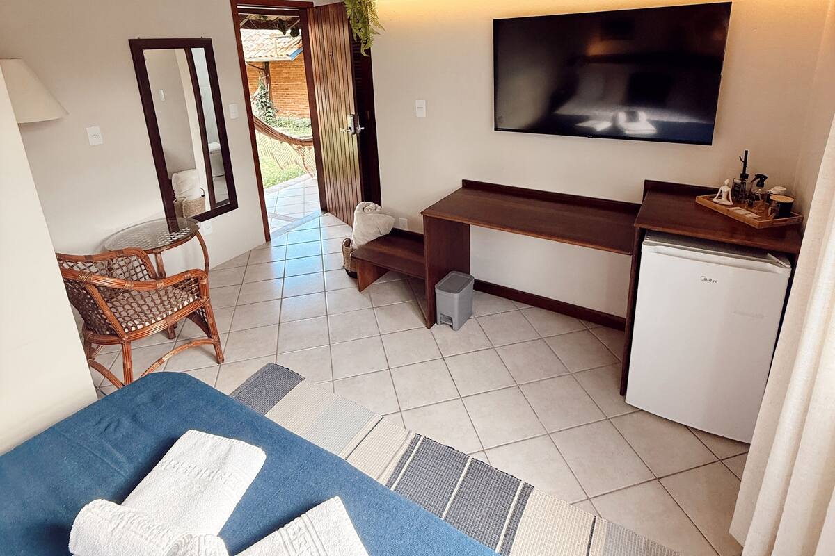 A hotel room with a bed, desk, TV, and a small fridge.