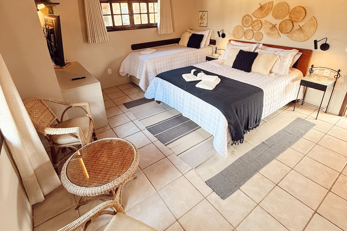 A bedroom with a bed, two bedside tables, a chair, a ceiling fan, and a window with curtains.
