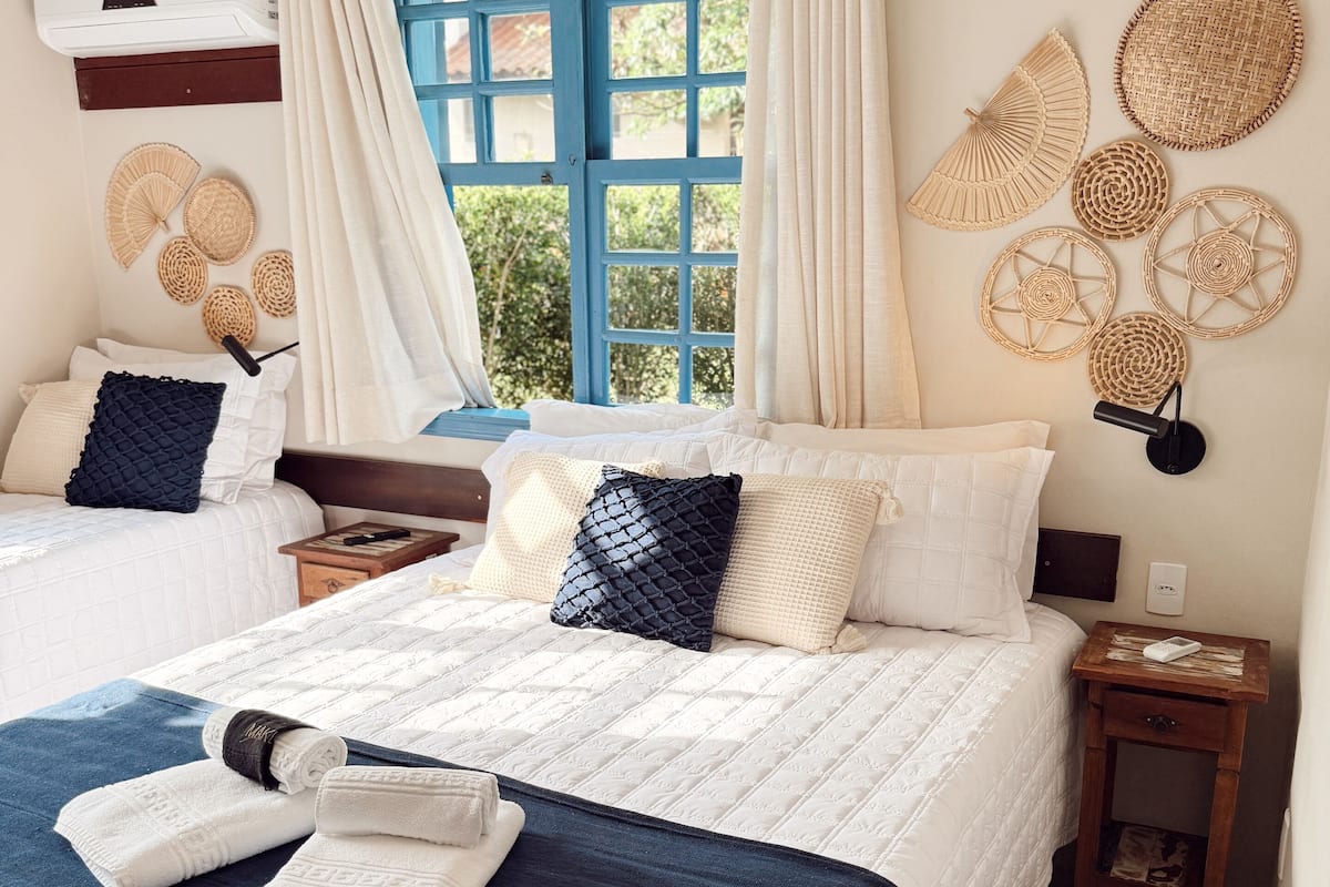A bedroom with a bed, two bedside tables, a window with curtains, and wall decor.