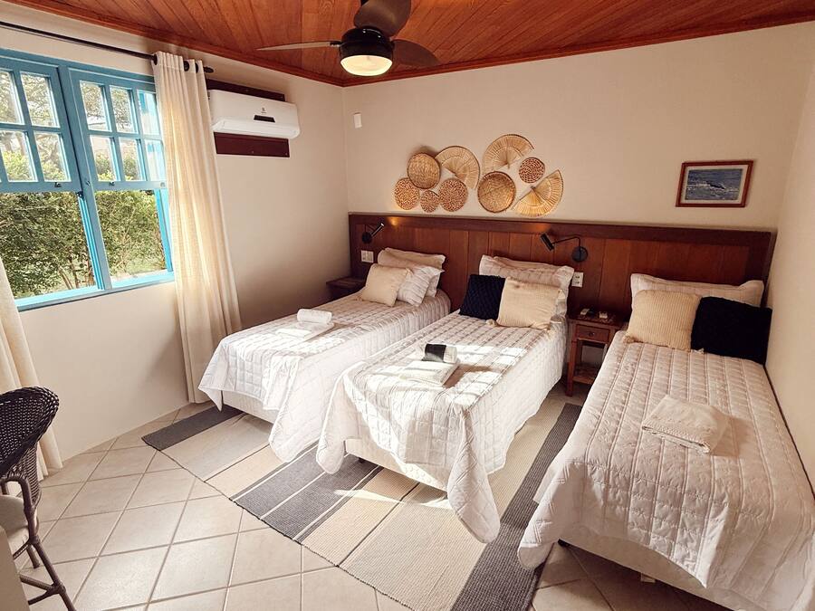 A room with two beds, a ceiling fan, a window with curtains, and a wall-mounted air conditioner.