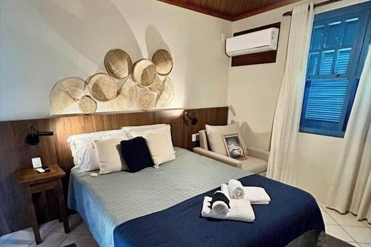 A neatly arranged bedroom with a bed, bedside tables, a ceiling fan, and a window with curtains.